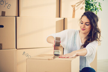 Young Caucasian girl using duct tape for packing carton boxes