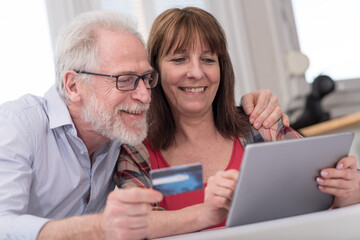 Mature couple shopping online with tablet and credit card