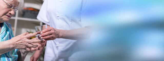 Obraz premium Nurse giving glass of water to senior woman
