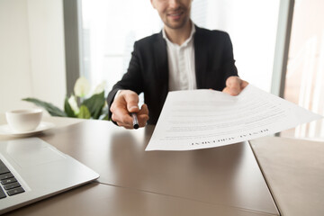 Realtor reaching out pen and rental agreement to clients. Real estate consultant sitting at desk in...