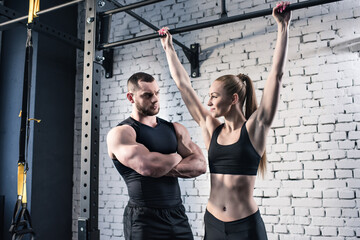 Fototapeta premium Athletic man and woman in sportswear exercising together in gym
