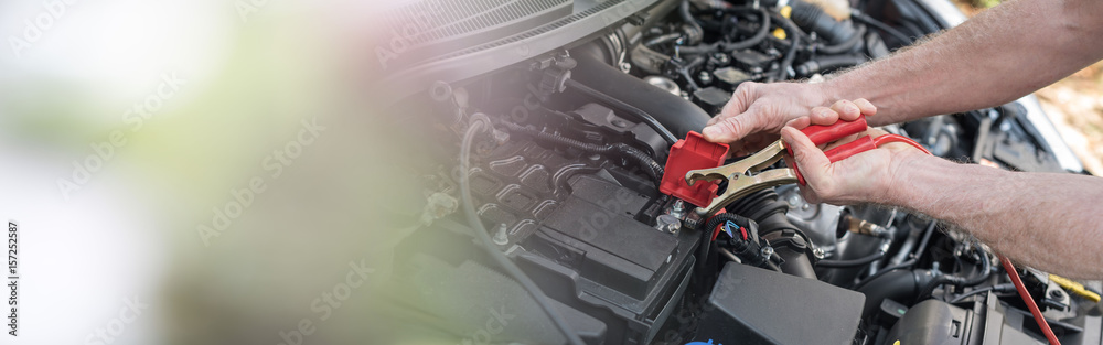 Wall mural hands of car mechanic using car battery jumper cable