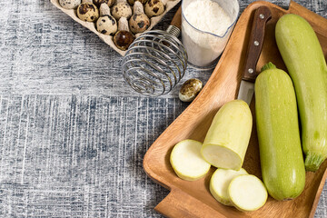 Zucchini. Fresh young zucchini courgettes on an old brown tray, next to a glass of flour and quail eggs.