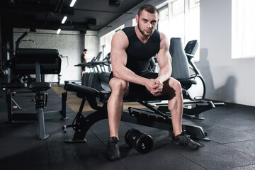 Fototapeta na wymiar young caucasian sportsman sitting at gym looking at camera
