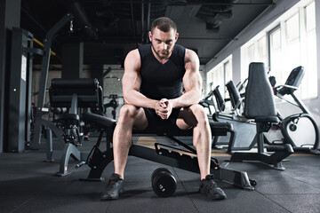 Fototapeta na wymiar young caucasian sportsman sitting at gym looking at camera