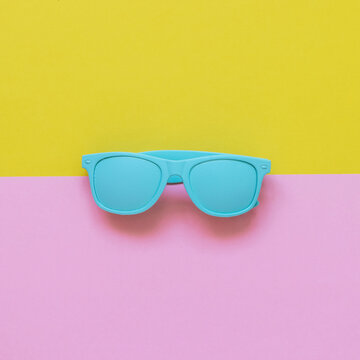 blue sunglasses on pink and yellow background. minimalism and summer fashion for the beach