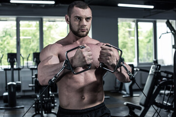 Fototapeta na wymiar young shirtless bodybuilder training with weight machine at gym