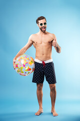 Full length portrait of a happy guy holding beach ball