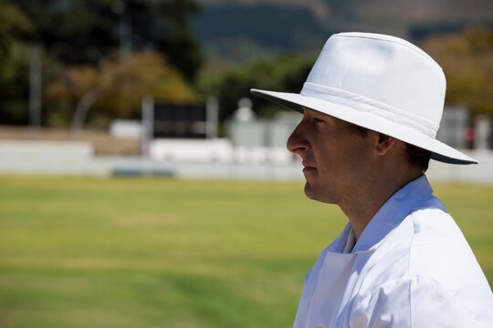 Profile view of umpire standing at field during cricket match - Powered by Adobe