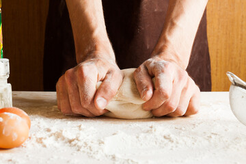 Man cooks in the kitchen preparing dough