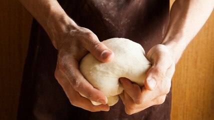 Naklejka premium Man cooks in the kitchen preparing dough