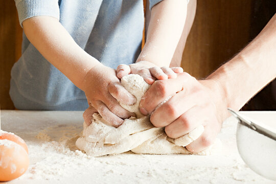 The child on the kitchen kneads the dough