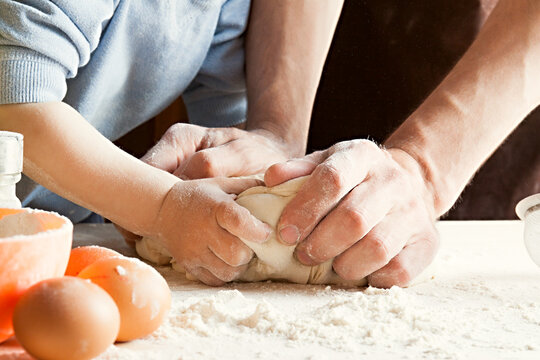 The son and father knead the dough.