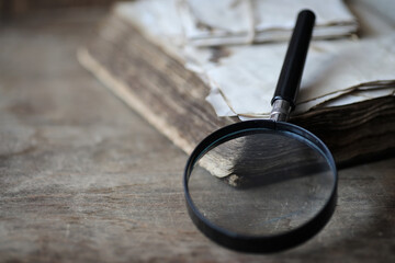 Old books on a wooden table and magnifier