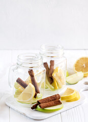 Two glass jars with ingredients for infused water on wooden board Detox fruit water