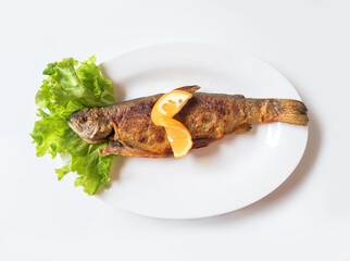 Grilled trout with orange lemon, salad leaves and french fries on white plate top view