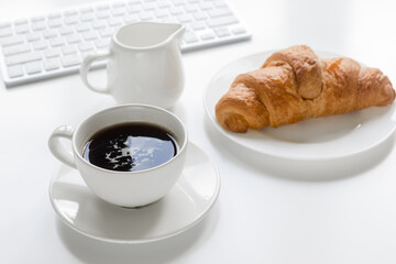 Businessman morning with keyboard, cup of coffee and croussant on white table background
