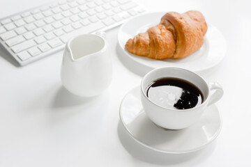 croissant and cup of coffee on office desk for business breakfast white background
