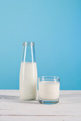 close up of milk in glass and bottle on tabletop at blue background