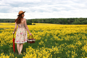 Fototapeta premium girl in a field of flowers with an umbrella and a hat