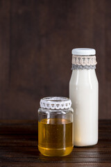 glass bottle of milk with honey in jar on wooden background