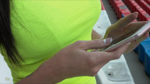 The girl stares at the phone at a sports stadium. Close-up