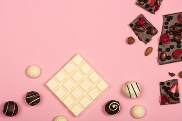 Top view of white chocolate, chocolate with nuts and fruits and sweet candies isolated on pink