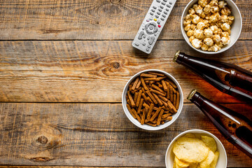 TV remote control, snacks, beer for whatchig film on wooden background top view space for text