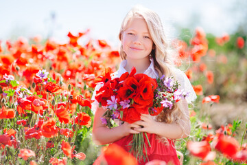 Naklejka premium Pretty child girl with bouquet of red poppies and purple flowers