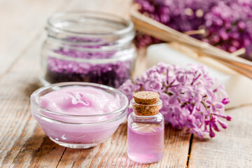 take bath with lilac cosmetic set and blossom on wooden table background