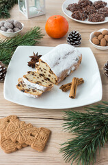 Arrangement of Gingerbread, Spiced Biscuits and Mini Christstollen on light wooden background surrounded by Christmas decoration.
