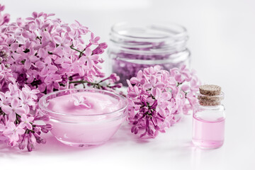 take bath with lilac cosmetic set and blossom on white table background