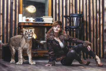 Beautiful fashionable young woman with a little alive lion cub