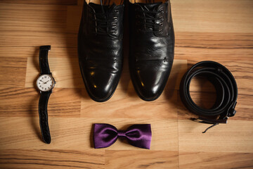 Men's accessories on wooden background. Shoes, bow tie, belt and wrist watch for business man
