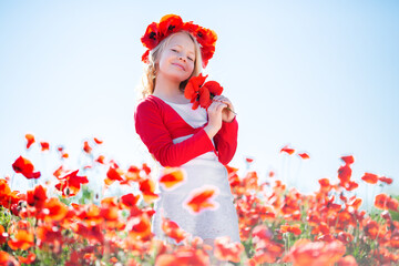 Happy blonde child girl in poppy field