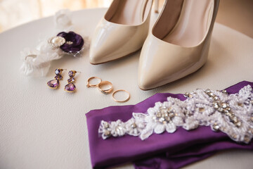 Wedding accessories for bride, bridal shoes on high heels near wedding rings, jewelry and garter...