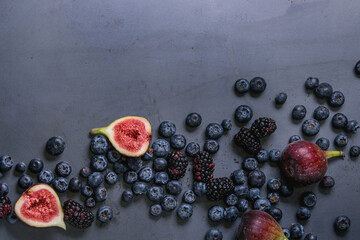 Variety of fresh berries blueberry, dewberry and figs over dark metal background. Top view with space.