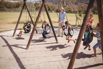 Trainer guiding schoolkids on swing