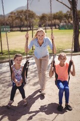 Portrait of trainer guiding schoolkids on swing