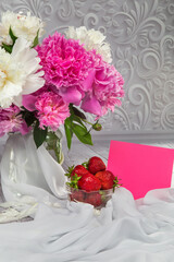 Obraz na płótnie Canvas Strawberries with a bouquet of peonies on a grey background
