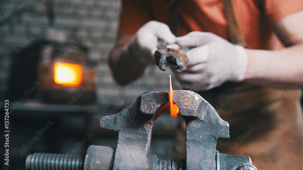 Wall mural blacksmith is bending iron rod with hammer - metal workshop, close up