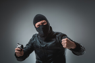 Burglar or terrorist in black mask shooting with gun.