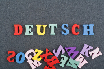 Deutsch, German word on black board background composed from colorful abc alphabet block wooden letters, copy space for ad text. Learning english concept