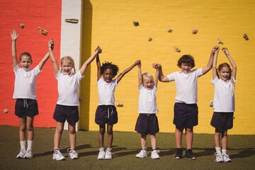 Happy schoolgirls standing with hand in hand