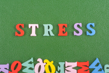 STRESS word on green background composed from colorful abc alphabet block wooden letters, copy space for ad text. Learning english concept.