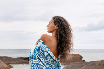 beautiful young woman wrapped in a blanket on the beach