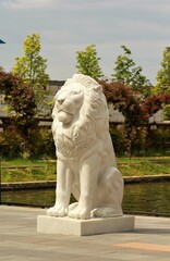 White marble statue of a lion against the park background, side view © Free_styler