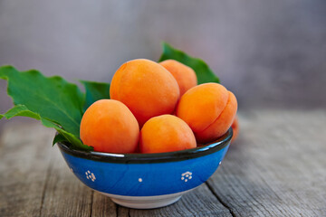 Fresh apricot in a blue bowl on rustic wooden table