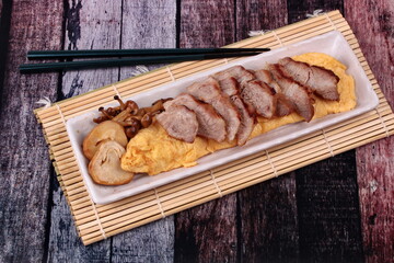 Omelet topped pork steak and grilled mixed mushroom.