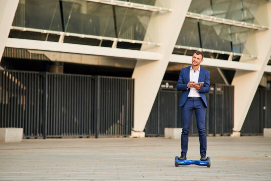 Young businessman on hoverboard outdoors. Guy wearing a suit.